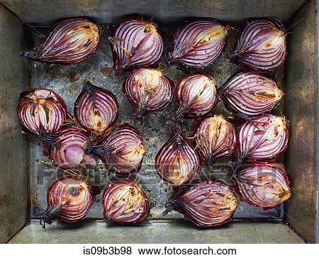 Stock Photo - Overhead view of roasted red onion halves with rosemary and olive oil in roasting tin. Fotosearch
