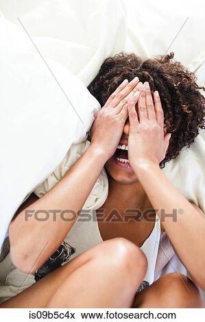 Stock Photo - Overhead view of woman lying on bed covering her eyes. Fotosearch