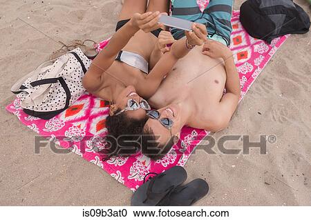 Overhead view of young couple taking smartphone selfie on Rockaway Beach, New York State, USA View Large Photo Image Stock Image - Overhead view of young couple taking smartphone selfie on Rockaway Beach, New York State, USA. Fotosearch
