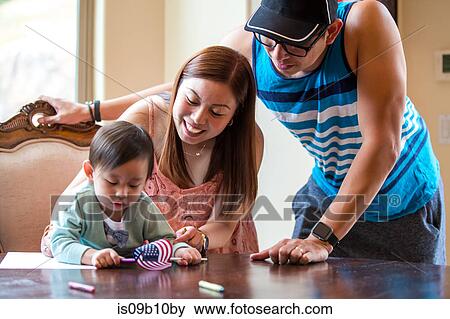 Stock Photo - Parents and baby boy with American flag, crayon drawing at dining room table. Fotosearch