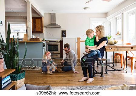 Stock Image - Parents in kitchen together with son and daughter. Fotosearch