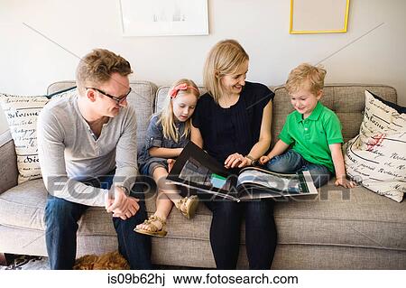 Parents on sofa reading storybook to son and daughter View Large Photo Image Stock Image - Parents on sofa reading storybook to son and daughter. Fotosearch