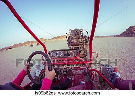 Stock Photograph - Personal perspective view of two people driving beach buggy in desert, Hurghada, Al Bahr al Ahmar, Egypt. Fotosearch