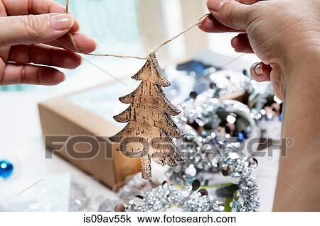 Stock Image - Person's hands preparing wooden christmas tree shaped christmas decoration. Fotosearch