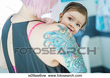 Portrait of baby boy peeking over his mothers tattoed shoulder View Large Photo Image Stock Photo - Portrait of baby boy peeking over his mothers tattoed shoulder. Fotosearch