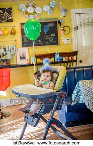 Portrait of baby boy wearing birthday party hat sitting in high chair View Large Photo Image Stock Image - Portrait of baby boy wearing birthday party hat sitting in high chair. Fotosearch