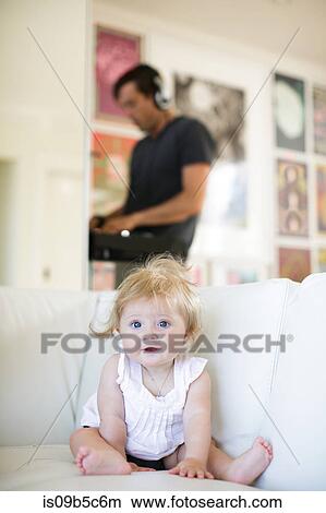 Picture - Portrait of baby girl sitting on sofa. Fotosearch