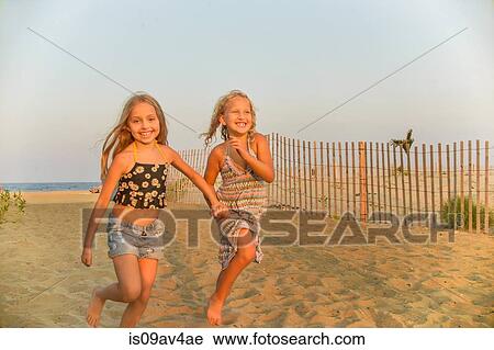 Portrait of blond haired sisters running hand in hand on beach View Large Photo Image Stock Image - Portrait of blond haired sisters running hand in hand on beach. Fotosearch