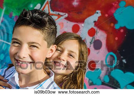 Portrait of boy and sister in front of wall mural at amusement park View Large Photo Image Stock Photo - Portrait of boy and sister in front of wall mural at amusement park. Fotosearch