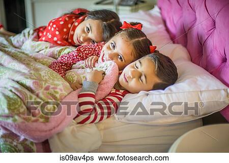 Portrait of boy and two sisters lying in bed View Large Photo Image Stock Photograph - Portrait of boy and two sisters lying in bed. Fotosearch