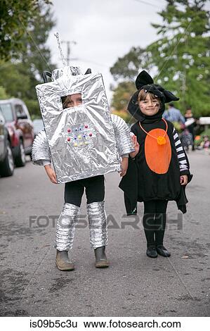 Stock Photograph - Portrait of boy in robot costume and girl in witch costume on street. Fotosearch