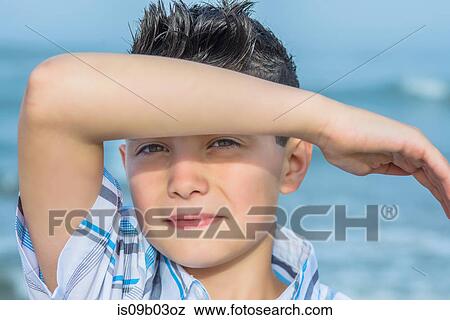 Portrait of boy shielding eyes on beach, Asbury Park, New Jersey, USA View Large Photo Image Stock Photo - Portrait of boy shielding eyes on beach, Asbury Park, New Jersey, USA. Fotosearch