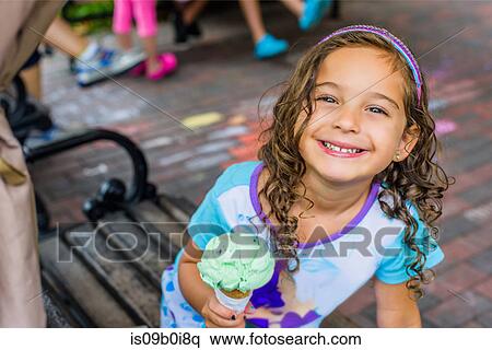 Portrait of cute girl eating ice cream cone on sidewalk View Large Photo Image Stock Photography - Portrait of cute girl eating ice cream cone on sidewalk. Fotosearch
