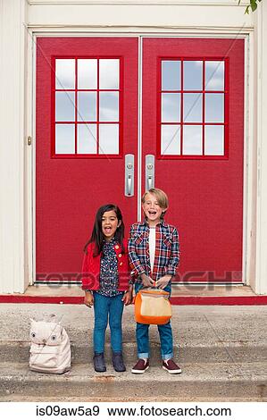 Portrait of elementary schoolgirl and boy with satchels at elementary school doorway View Large Photo Image Stock Photo - Portrait of elementary schoolgirl and boy with satchels at elementary school doorway. Fotosearch