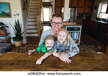 Picture - Portrait of father at kitchen table with daughter and son. Fotosearch