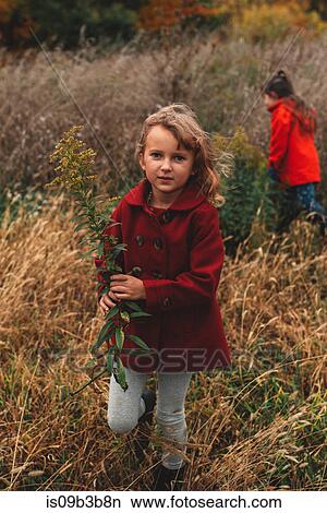 Portrait of girl and her sister picking wildflowers in field View Large Photo Image Picture - Portrait of girl and her sister picking wildflowers in field. Fotosearch