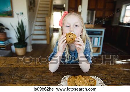 Portrait of girl eating muffin at kitchen table View Large Photo Image Stock Image - Portrait of girl eating muffin at kitchen table. Fotosearch