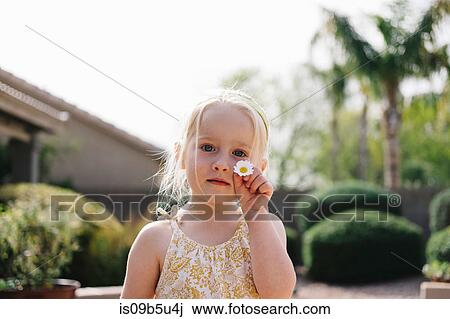 Stock Image - Portrait of girl holding daisy flower. Fotosearch