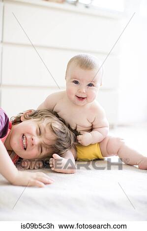 Portrait of happy baby girl pulling big brother's hair on bed View Large Photo Image Stock Image - Portrait of happy baby girl pulling big brother's hair on bed. Fotosearch