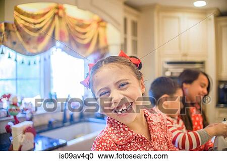 Stock Image - Portrait of happy girl with brother and sister in kitchen. Fotosearch