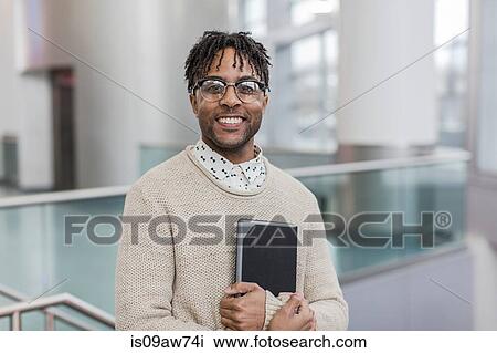 Stock Image - Portrait of happy young businessman standing in train station holding digital tablet. Fotosearch