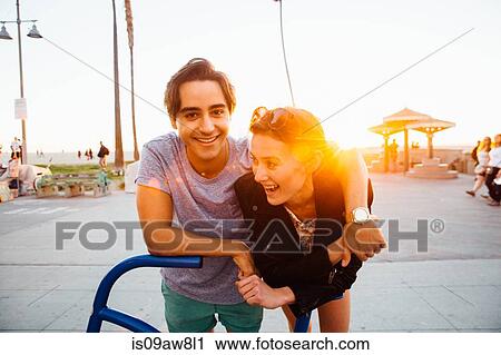 Portrait of happy young couple leaning against bicycle sculpture at coast, Venice Beach, California, USA View Large Photo Image Stock Image - Portrait of happy young couple leaning against bicycle sculpture at coast, Venice Beach, California, USA. Fotosearch