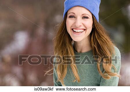 Stock Image - Portrait of happy young woman wearing knit hat. Fotosearch