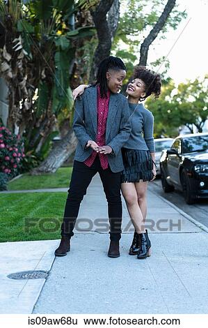 Stock Photograph - Portrait of lesbian couple, outdoors, smiling. Fotosearch