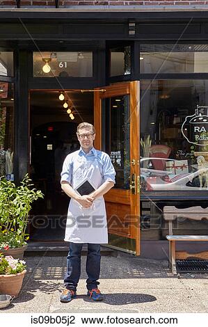 Stock Image - Portrait of male worker, standing outside bakery. Fotosearch