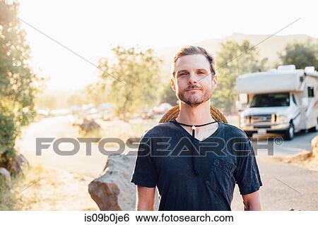Stock Photograph - Portrait of man by camper van looking at camera, Malibu Canyon, California, USA. Fotosearch