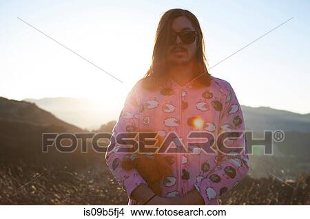 Picture - Portrait of man wearing pink pyjamas holding teddy bear, Malibu Canyon, California, USA. Fotosearch