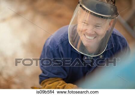 Picture - Portrait of man wearing welding mask smiling. Fotosearch