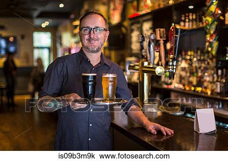 Portrait of mature bartender carrying tray of beer in public house View Large Photo Image Stock Image - Portrait of mature bartender carrying tray of beer in public house. Fotosearch