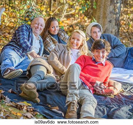 Portrait of mature couple with teenage and adult children relaxing on picnic blanket in woods View Large Photo Image Picture - Portrait of mature couple with teenage and adult children relaxing on picnic blanket in woods. Fotosearch