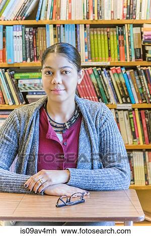 Stock Image - Portrait of mature female student in front of bookshelf. Fotosearch
