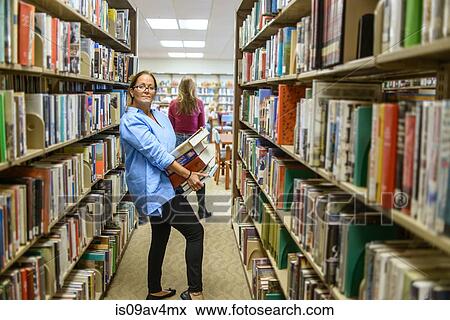 Portrait of mature woman carrying stack of books from library shelves View Large Photo Image Stock Photo - Portrait of mature woman carrying stack of books from library shelves. Fotosearch