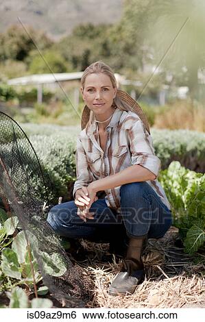 Portrait of mature woman crouching in garden View Large Photo Image Stock Photograph - Portrait of mature woman crouching in garden. Fotosearch