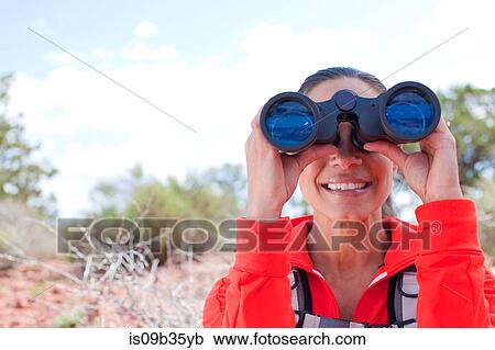 Stock Image - Portrait of mature woman looking through binoculars, Sedona, Arizona, USA. Fotosearch