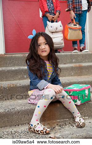 Picture - Portrait of nervous elementary schoolgirl sitting on elementary school stairs. Fotosearch