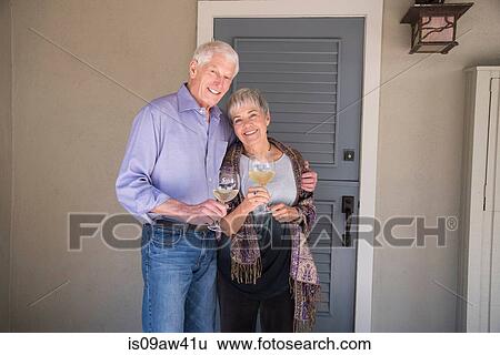 Stock Photograph - Portrait of senior couple, holding glass of wine, smiling. Fotosearch