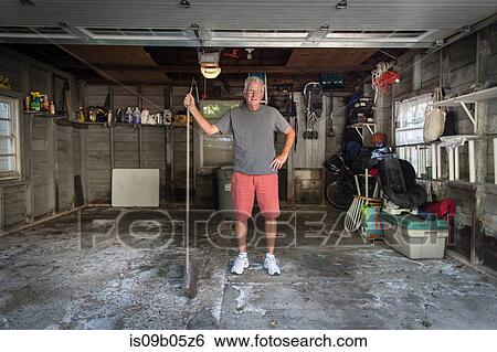 Portrait of senior man standing in garage holding broom View Large Photo Image Stock Photograph - Portrait of senior man standing in garage holding broom. Fotosearch