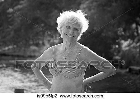 Stock Image - Portrait of senior woman in bikini looking at camera smiling. Fotosearch