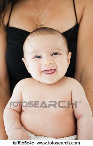 Stock Image - Portrait of smiling baby girl on mother's lap. Fotosearch