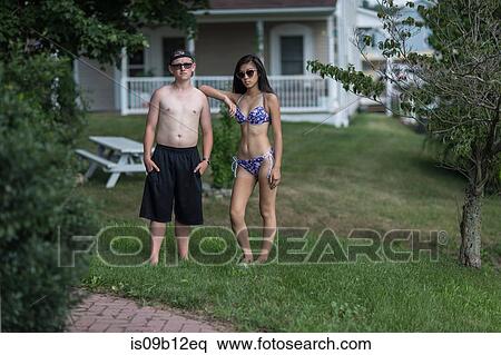 Portrait of sullen teenage couple wearing swimming shorts and bikini in garden View Large Photo Image Stock Photography - Portrait of sullen teenage couple wearing swimming shorts and bikini in garden. Fotosearch