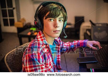 Portrait of teenage boy sitting at home desk wearing headset View Large Photo Image Picture - Portrait of teenage boy sitting at home desk wearing headset. Fotosearch