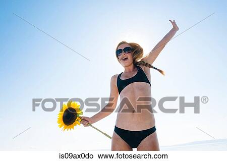 Portrait of teenage girl wearing bikini, holding sunflower, arm raised View Large Photo Image Picture - Portrait of teenage girl wearing bikini, holding sunflower, arm raised. Fotosearch