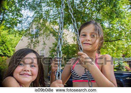 Portrait of two cute sisters playing on swing in garden View Large Photo Image Stock Image - Portrait of two cute sisters playing on swing in garden. Fotosearch