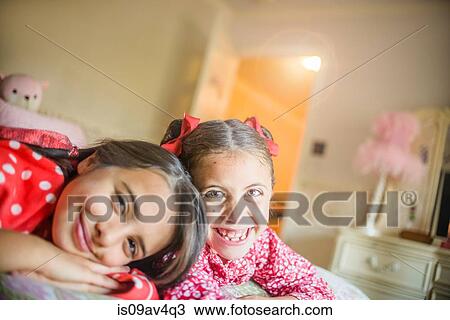 Portrait of two happy sisters lying on bed View Large Photo Image Stock Image - Portrait of two happy sisters lying on bed. Fotosearch
