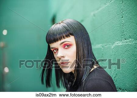 Portrait of woman leaning against painted breeze block wall looking at camera View Large Photo Image Picture - Portrait of woman leaning against painted breeze block wall looking at camera. Fotosearch