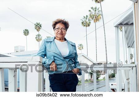 Stock Image - Portrait of woman on porch looking at camera smiling. Fotosearch